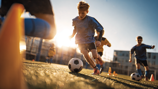 Youth soccer players warming up by dribbling through cones.